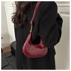 Sac demi-lune en cuir verni rouge brillant porté par un mannequin vue de côté