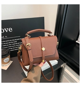Detail of brown pebbled leather texture on retro crossbody bag with gold buckle