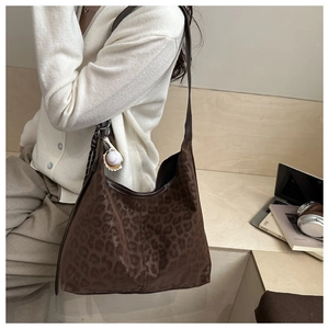 Brown leopard print shoulder bag with baseball charm shown in a lifestyle setting