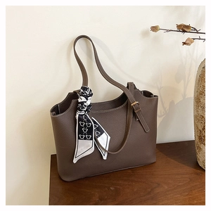 Dettaglio della borsa tote in pelle marrone caffè con sciarpa di seta a motivi geometrici