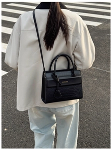 Détail d'un sac à main en cuir noir gaufré crocodile avec lettrage doré chic