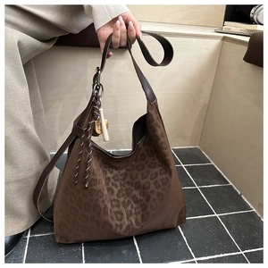 Detail of hobo shoulder bag with leopard print texture and decorative tassel pendant