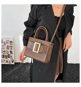 Brown matte leather tote bag with a prominent gold square buckle shown on a model