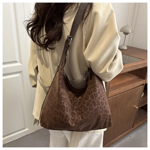 Detail of large leopard print hobo bag worn by model, showing texture and wide strap