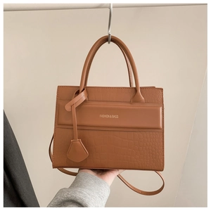 Gros plan sur la texture crocodile marron et lettrage doré d'un grand sac à main