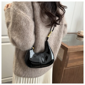 Détail du sac demi-lune en cuir verni noir avec finition brillante et boucle dorée