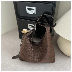 Brown leopard print Hobo bag with plush hedgehog charm on a grey carpet