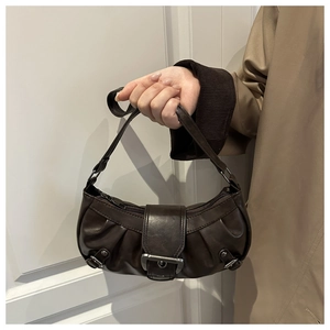 Detail of dark brown pleated crescent bag featuring matte silver buckle closure and leather texture