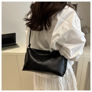 Détail du sac minimaliste noir avec couture verticale porté par un mannequin