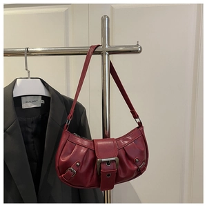 Close-up of retro dark red pleated shoulder bag with large metal buckle detail