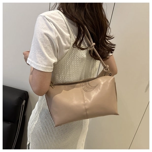 Détail du sac beige avec nœud sur la bandoulière et fermeture éclair métallique