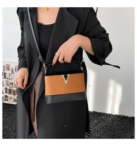 Close-up of brown suede and black leather shoulder bag with quilted V-shaped gold logo