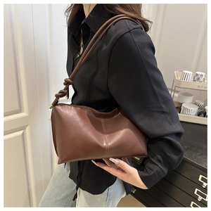 Détail du sac sous le bras marron foncé avec noeud élégant sur la bandoulière en cuir