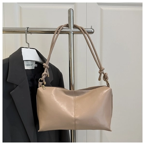 Détail de la bandoulière nouée et couture verticale sur le sac beige porté épaule