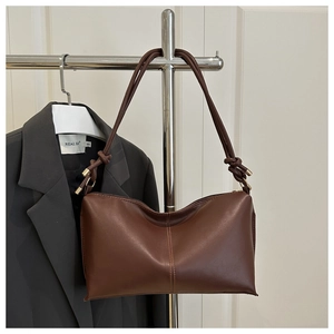 Détail du sac à bandoulière en cuir marron foncé avec sangle nouée et boucles dorées