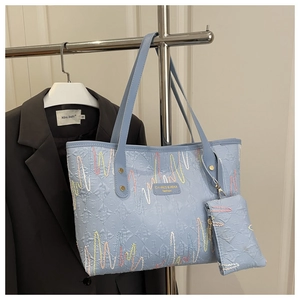 Detail of light blue embroidered tote bag with colorful wave patterns and a small coin purse