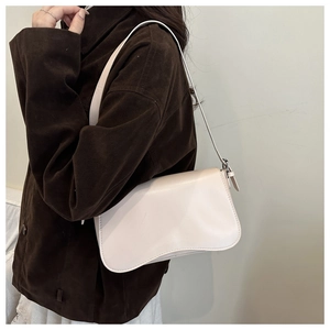 Detail view of light beige shoulder bag featuring a unique wavy bottom design and matte leather