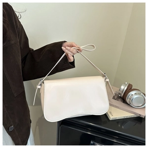 Detail of beige faux leather shoulder bag with curved bottom and flap closure