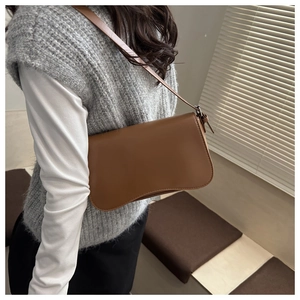 Close-up of a matte brown vintage underarm bag with a curved base and thin shoulder strap