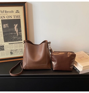 Brown vintage faux leather tote bag and matching pouch set on a rustic wooden table
