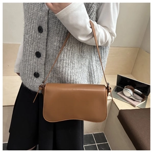 Minimalist caramel brown leather shoulder bag shown in a stylish urban lifestyle setting