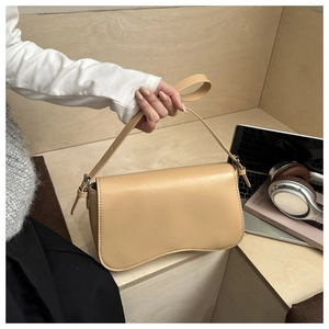 Detail of minimalist cream leather shoulder bag with a unique wavy base and silver buckle