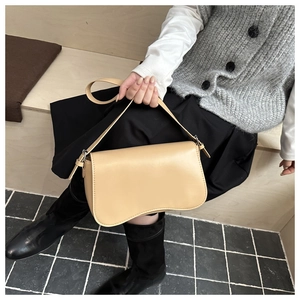 Detail of light khaki shoulder bag with a unique wave-shaped bottom and smooth leather finish