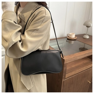 Minimalist black matte leather shoulder bag styled with a khaki trench coat in cozy room