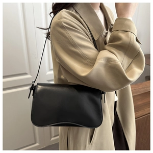 Close-up of a black matte leather underarm bag with minimalist rounded edge design
