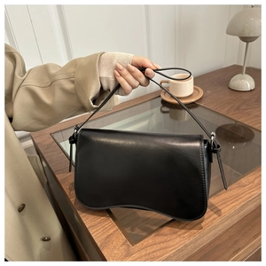 Close-up of black retro matte shoulder bag with silver buckle on a wooden desk