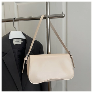 Detail of cream minimalist underarm bag with silver buckle and curved bottom design
