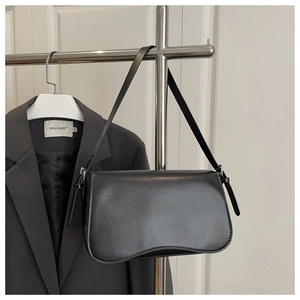 Detail of matte black leather shoulder bag with flap closure and adjustable strap