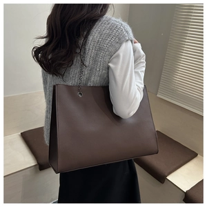 Macro shot of dark chocolate brown tote bag with premium lychee grain texture and metal chain
