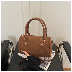 Détail du logo gaufré sur le sac polochon en daim marron avec des ferrures dorées