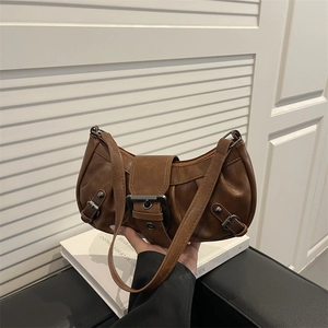 Brown vintage pleated shoulder bag with large metal buckle in a handheld lifestyle view