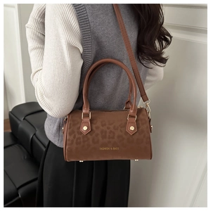 Detail of leopard print boston bag featuring gold text and slender shoulder strap
