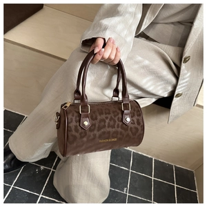 Detail of a dark brown leopard print barrel handbag with gold hardware and twin handles