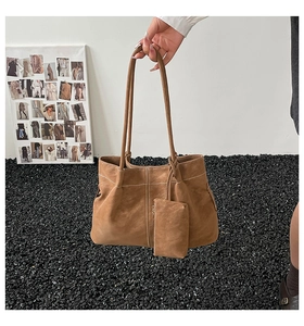 Detail of brown suede tote bag with white contrast stitching and mini pouch charm