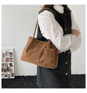 Detail of vintage brown suede tote with white contrast stitching and matching pouch charm