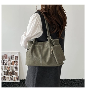 Olive green suede tote bag detail featuring white contrast stitching and a knotted strap