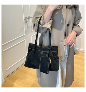 Detail of black suede tote bag featuring white contrast stitching and matching small pouch
