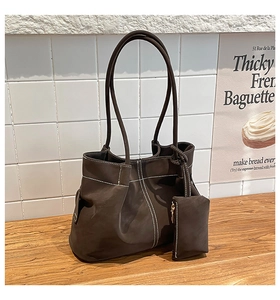 Detail of dark brown tote bag featuring white contrast stitching and matching pouch
