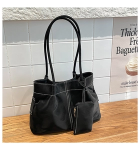 Detail view of black faux leather tote with white contrast stitching and a small coin pouch