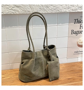 Detail of moss green suede tote bag with white stitching and matching coin purse charm