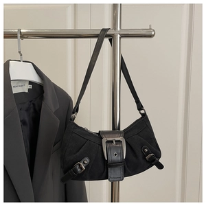 Detail of a black baguette shoulder bag with silver buckle on a steel hanger