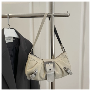 Close-up of beige ruched dumpling bag with large silver metal buckle on grey blazer