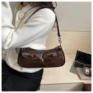 Detail view of dark brown patent leather shoulder bag with glossy finish and metal ring