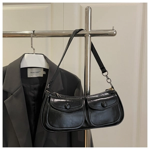 Detail of glossy black shoulder bag with dual pockets and adjustable strap for women