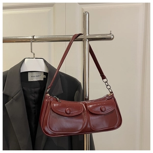 Detail of dark red faux leather shoulder bag with vintage buckles and metal zippers