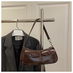 Macro detail of dark brown oil-wax leather shoulder bag with decorative double pockets